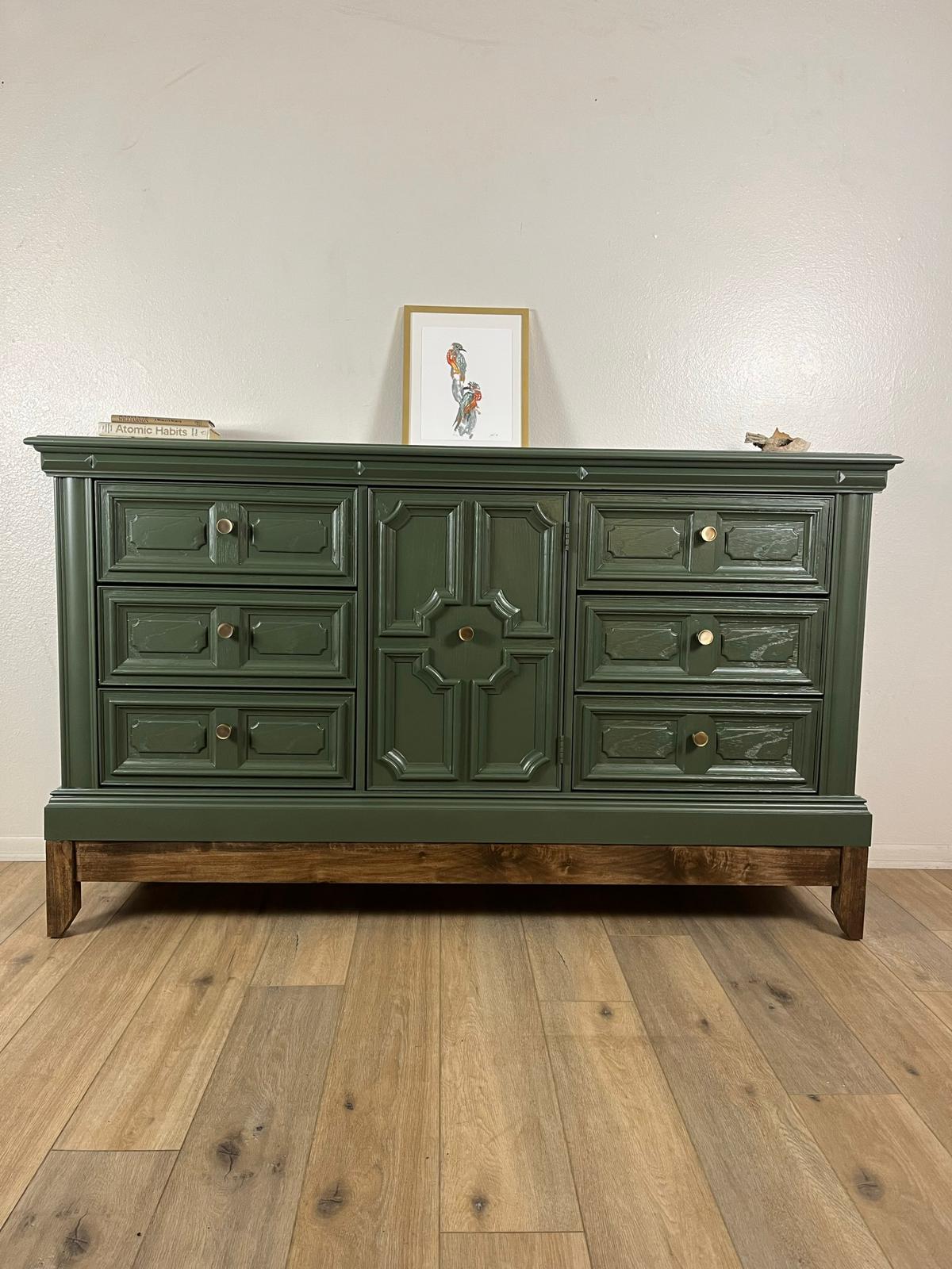 Green dresser with six outer drawers, a central paneled door and a visible wood base