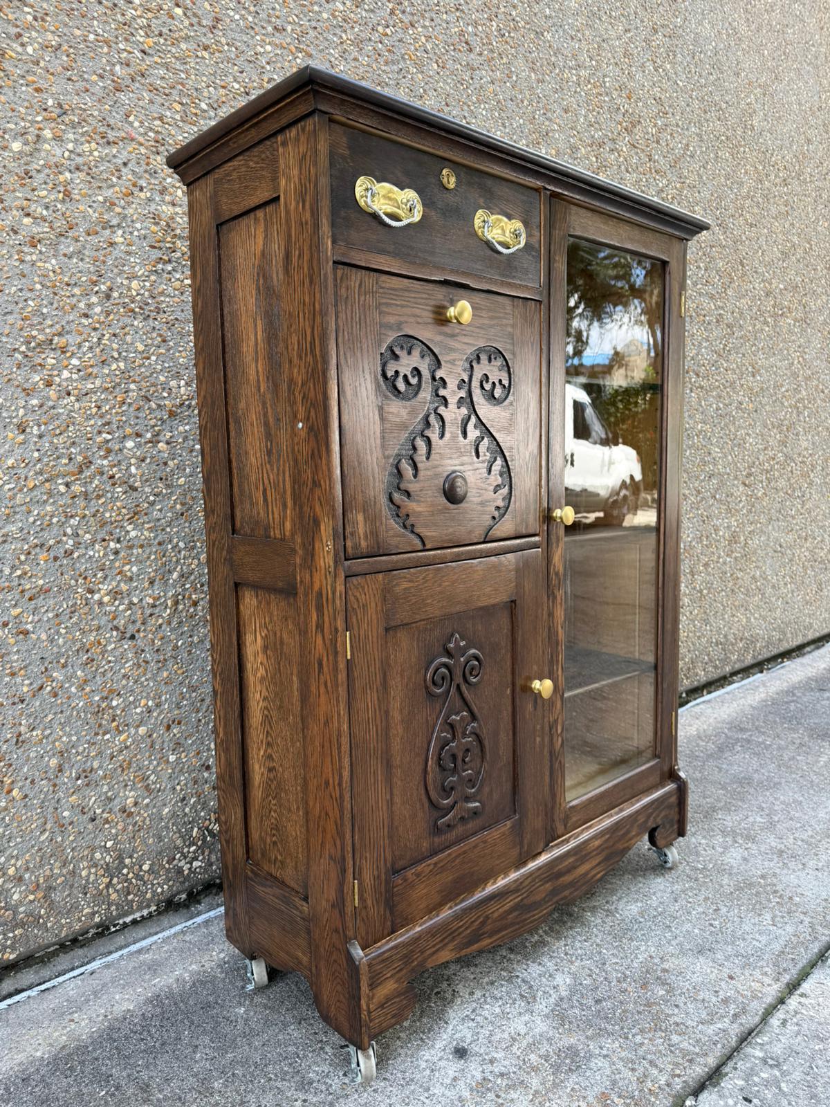 Assembled ornate cabinet with dark wood finish, carved door panels and bright metal handles